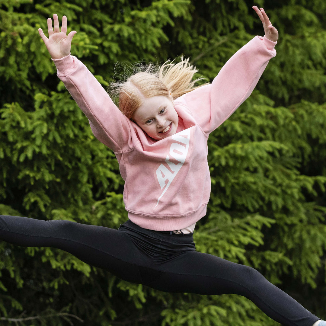 Ein glückliches Mädchen in einem Acon-Shirt springt auf einem Trampolin.