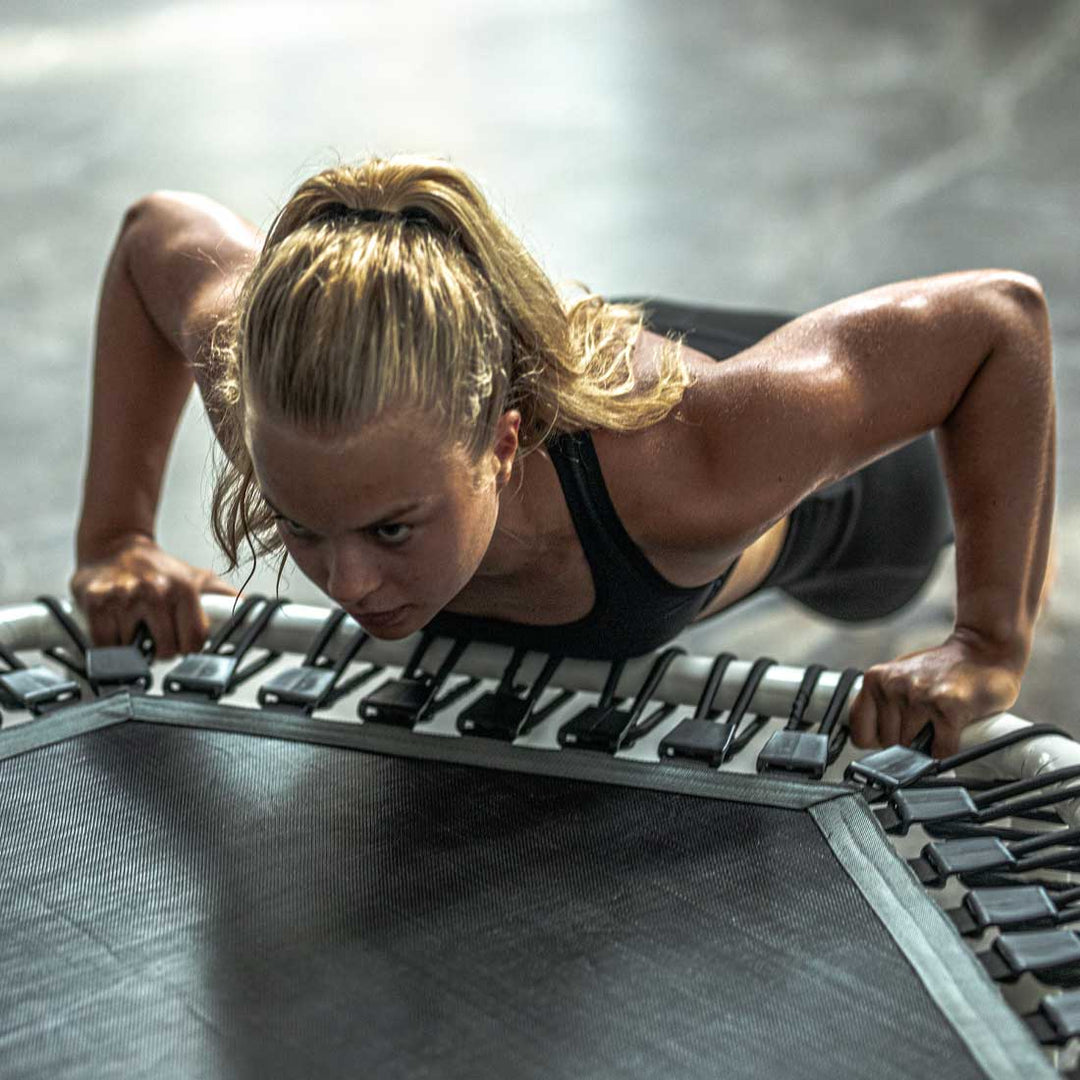 Frau beim Training auf dem Acon FIT 1,41m Hexagon Trampolin weiß.