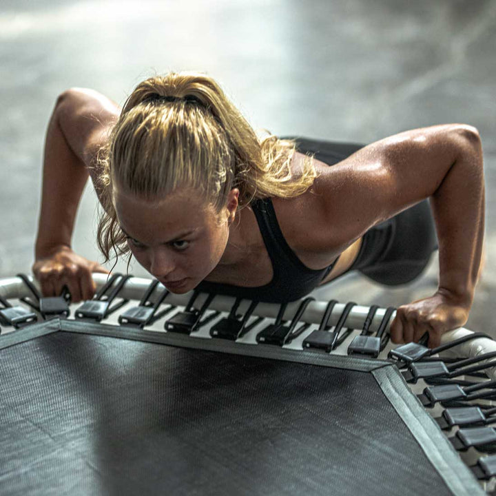 Frau beim Training auf dem Acon FIT 1,41m Hexagon Trampolin weiß.
