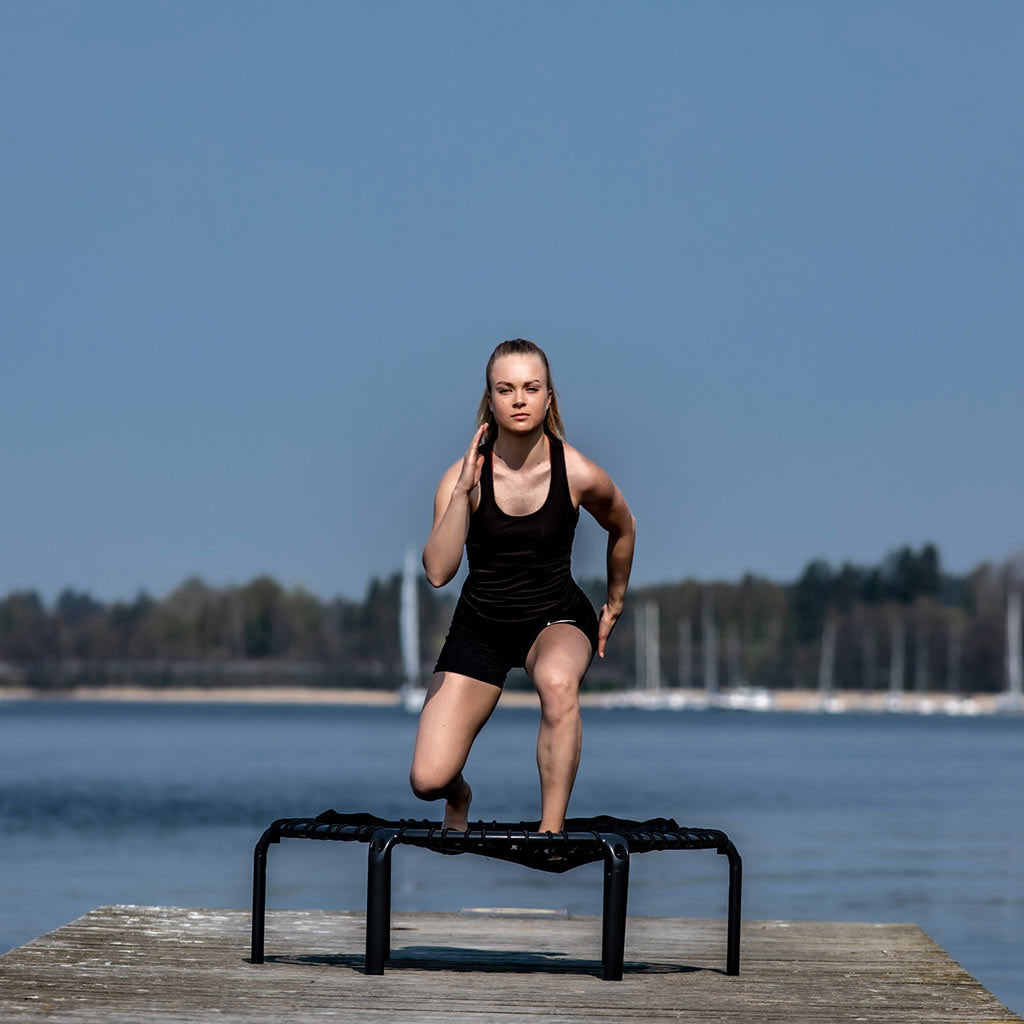 Mädchen beim Outdoor-Training auf dem ACON FIT Hexagon-Trampolin am See.